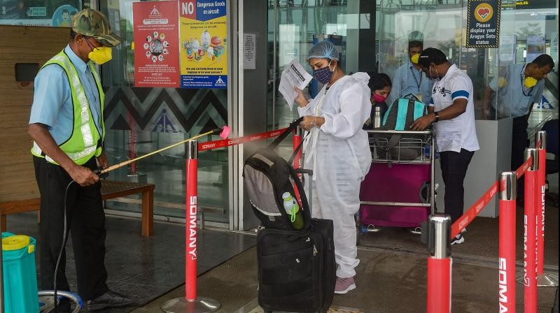 Workers sanitise passenger baggage in front of the entry gate at NSCBI Airport, during weekly two-day complete lockdown to curb the spread of coronavirus disease, in Kolkata. (PTI)